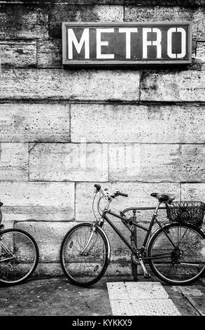 Paris Métro signe au-dessus un vélo garé contre un mur de blocs de pierre. Noir et blanc. Copier l'espace. Style graphique réaliste Banque D'Images
