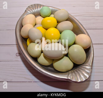 Un plateau d'argent remplis d'oeufs de Pâques de diverses couleurs portant sur une table en bois Banque D'Images