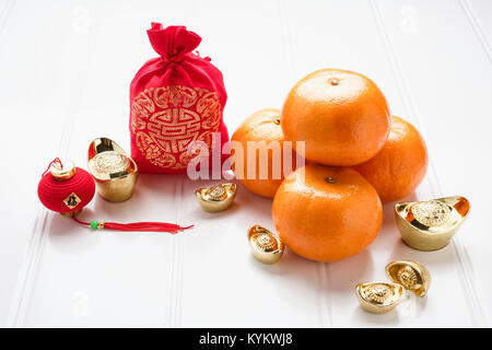 Le nouvel an chinois,ang pow feutre rouge sac en tissu avec des lingots d'or et la mandarine des oranges sur la table en bois blanc Langue chinoise,le bonheur et la moyenne sur ing Banque D'Images