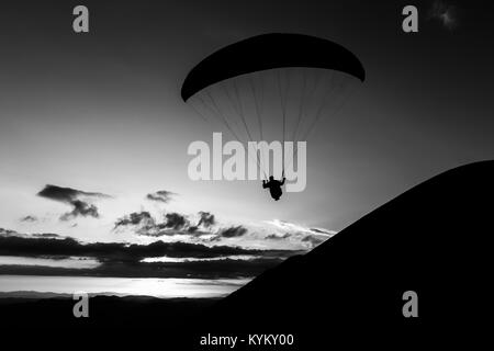 Beau coup d'une silhouette parapente voler au-dessus de Monte Cucco (Ombrie, Italie), avec le coucher du soleil sur l'arrière-plan Banque D'Images