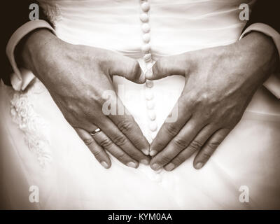 Le marié la création de forme de coeur avec ses mains sur le dos de la mariée.Couple dans l'amour. Close up of hands. Jeune couple a fait mains en forme de coeur en t Banque D'Images