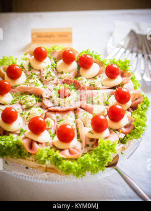 Un petit gâteau avec saucisses, fromage, salade et tomates Banque D'Images