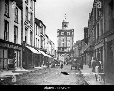 Un négatif en verre montrant South main Street et la porte de l'horloge à Youghal, dans le comté de Washington. Le liège, capturé au début du XXe siècle, présente la vie de rue et les monuments. Banque D'Images
