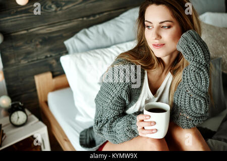 Femme sérieuse avec du café à la recherche d'une fenêtre Banque D'Images