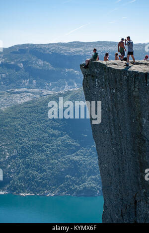 Homme assis sur le bord du rocher Pulpit - Preikestolen se trouve une falaise qui s'élève à 604 mètres au-dessus du Lysefjorden en Norvège Banque D'Images