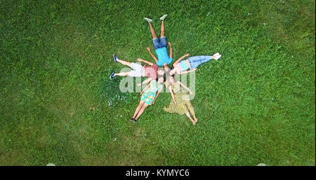 Groupe de jeunes adultes laying in grass dans la formation des étoiles Banque D'Images