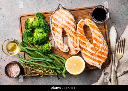 Découper avec des darnes de saumon grillées et de légumes sur le tableau gris, vue du dessus Banque D'Images
