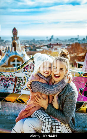 Barcelona style exclusif. Portrait of a modern la mère et l'enfant du voyage à Barcelone, Espagne hugging tout en restant assis sur un banc Banque D'Images