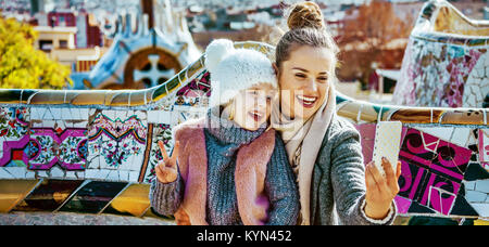 Barcelona style exclusif. Portrait of smiling trendy mère et fille les touristes à Barcelone, Espagne avec le smartphone en tenant assis sur selfies Banque D'Images