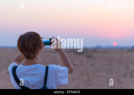 Femme smart phone photo coucher du soleil du désert. Photographie touristique le désert du Namib, coucher de soleil, ciel romantique destination voyage en Namibie, d'Afrique. Les gens t Banque D'Images