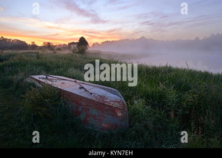 Bateau de pêche avec de pêcheurs se trouve sur les bords de la rivière dans la brume matinale Banque D'Images