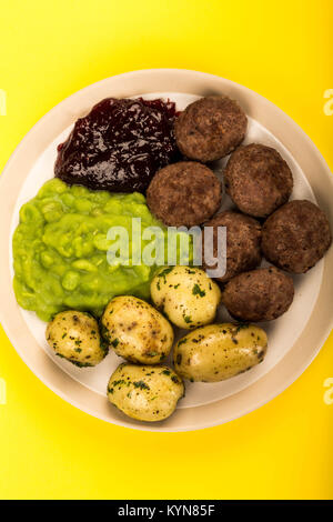 Norvégien ou suédois avec boulettes de petits pois pommes de terre bouillies et de la sauce aux canneberges sur fond jaune Banque D'Images