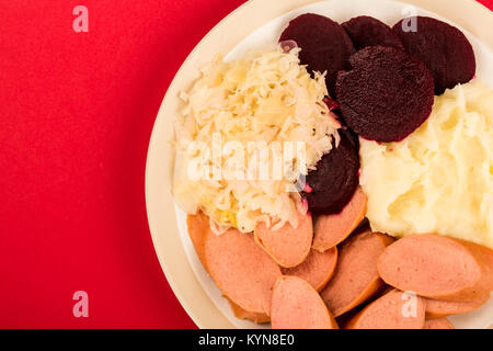 Le suédois ou le norvégien de la saucisse avec de la purée de pommes de terre et betteraves Repas choucroute sur un fond rouge Banque D'Images