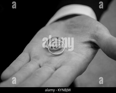 Les anneaux de mariage en main de mariés - Photographie noir et blanc Banque D'Images