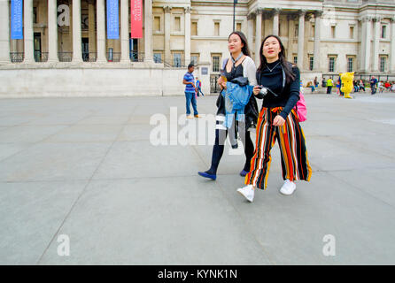 Londres, Angleterre, Royaume-Uni. Deux touristes asiatiques passant la National Gallery, Trafalgar Square Banque D'Images