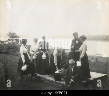 Photographie Ancienne vers 1905, famille à la pompe à eau avec rivière en arrière-plan. L'emplacement est dans ou près de Riggsville (maintenant) dans le Maine, Robinhood de Sagadahoc, USA. Banque D'Images