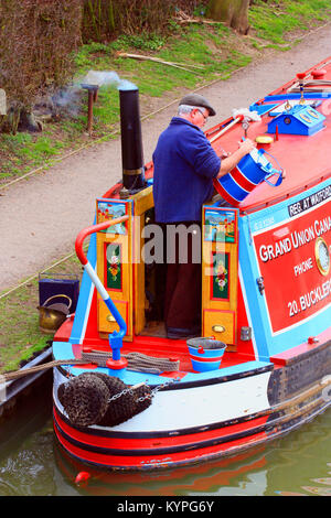 15-04 main propriétaire un seau de peinture à bord de son bateau sur le Canal Grand Union Banque D'Images