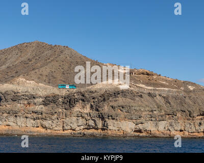 Gran Canaria, îles Canaries en Espagne - 16 décembre. 2016 : Blue bus roulant sur la route dans les montagnes abruptes sur la côte entre Puerto de Mogan et Puerto Rico. Couches de roche volcanique. Strata. Banque D'Images