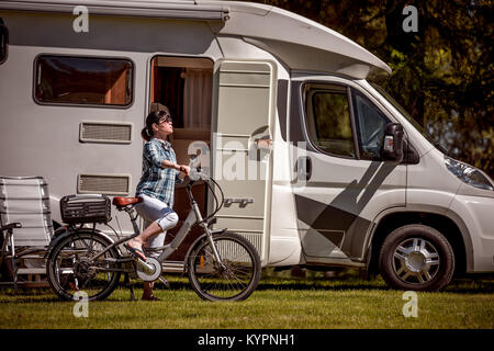 Femme sur vélo électrique reposant sur le camping. Vacances famille vacances, voyages voyage en camping-car, caravane locations de voiture VR. Banque D'Images