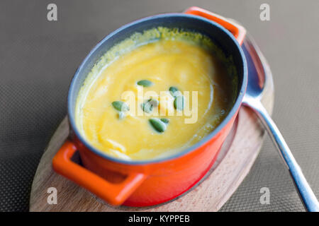 Crème de potiron épais-soupe dans un rouge miniature pot en fonte sur un support en bois. Servir dans un café. Vue d'en haut. Banque D'Images