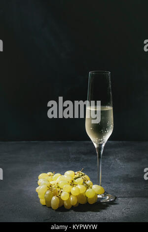 Un verre de champagne avec des raisins blanc vert foncé sur fond de texture. Copy space Banque D'Images