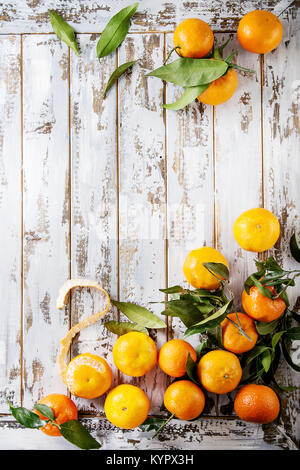 Clémentines ou mandarines biologiques mûrs avec des feuilles sur planche en bois blanc table comme arrière-plan. Vue de dessus, de l'espace. La saine alimentation Banque D'Images