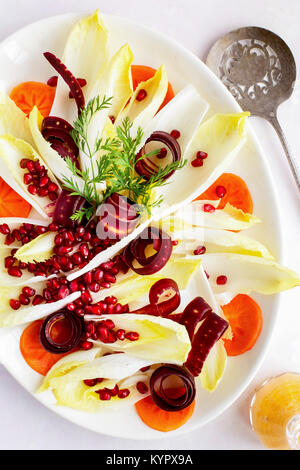 Salade d'endives avec une vinaigrette Chevre de kaki. Photographié sur un fond lilas clair. Banque D'Images