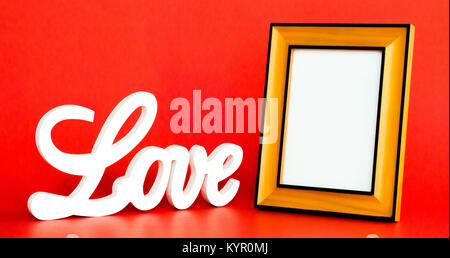 L'amour blanc signe en lettres cursives avec un cadre photo vide à personnaliser sur fond rouge Banque D'Images