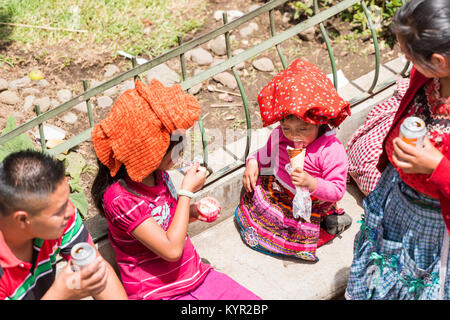 SAN JUAN OSTUNCALCO, GUATEMALA - le 24 juin : Une jeune fille en costume traditionnel avec d'autres personnes non identifiée bénéficiant d'une glace sur un pied d'égalité Banque D'Images