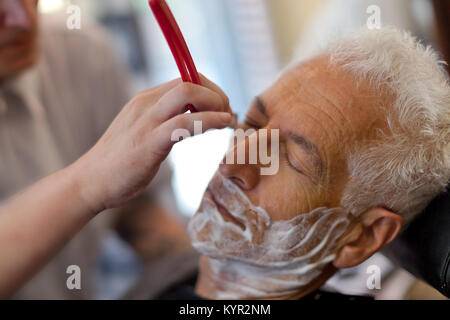 L'obtention d'un vieil homme se raser avec un bord droit à un rasoir de barbier. Close up Banque D'Images