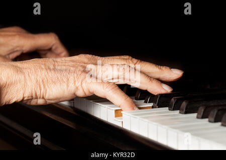 Vieilles mains jouant du piano. Close up of fingers et touches de piano sur fond noir. Copier l'espace. Banque D'Images