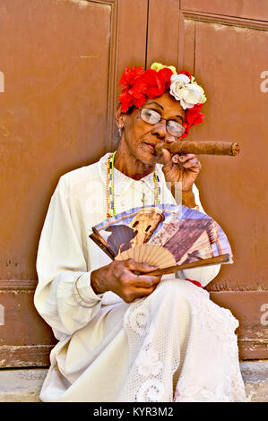 La HAVANE, CUBA, le 6 mai 2009. Une vieille femme assise avec un énorme cigare dans sa bouche et roses dans sa tête à La Havane, Cuba, le 7 mai 2009. Banque D'Images