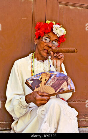 La HAVANE, CUBA, le 6 mai 2009. Une vieille femme assise avec un énorme cigare dans sa bouche et roses dans sa tête à La Havane, Cuba, le 7 mai 2009. Banque D'Images