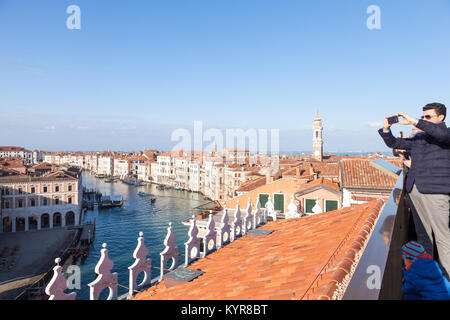 Les touristes en observant le Grand Canal et toits de Venise du Fondaco dei Tedeschi toit-terrasse avec un homme de prendre une photographie de téléphone mobile Banque D'Images