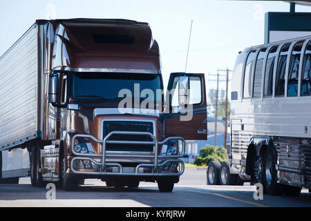 Luxe moderne pearl brown bonnet gros camion semi truck avec porte ouverte et l'auvent protecteur d'effectuer semi-remorque frigorifique sur arrêt de camion en ligne Banque D'Images