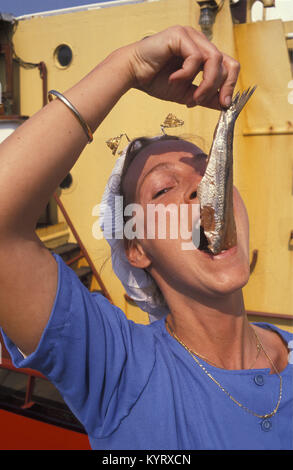 Les Pays-Bas, Scheveningen, près de La Haye ou Den Haag. Femme en costume traditionnel de manger du hareng dans la manière typique des Pays-Bas. Banque D'Images