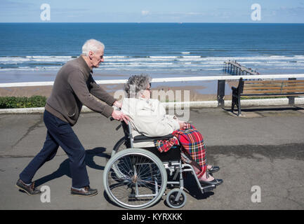 Vieil homme edlerly poussant woman in wheelchair sur front de mer. UK Banque D'Images