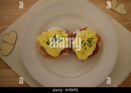 La photographie alimentaire image d'un petit-déjeuner ou un brunch d'oeufs Benedict sur plaque blanche avec fond bois prises dans Chichester Banque D'Images