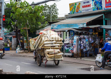 Remorque moto précairement surchargé d'un chargement de caisses : scène de rue en milieu urbain typique de Saigon (Ho Chi Minh Ville), le Vietnam du Sud, en Asie du sud-est Banque D'Images