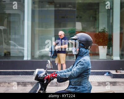 Motocycliste féminin portant un casque de sécurité plus de mal d'un chapeau et d'une capuche : scène de rue à Saigon (Ho Chi Minh Ville), le sud Vietnam Banque D'Images