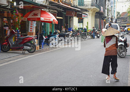 Hanoi, Vietnam - 14 décembre 2017. Une femme âgées en vêtements traditionnels et hat marche dans une rue dans le vieux quartier historique de Hanoi Banque D'Images