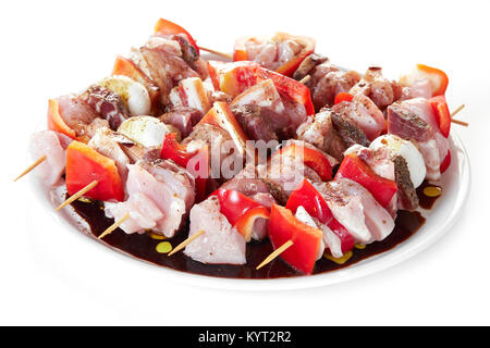 Brochettes avec des morceaux de viande, le poivron rouge, le bacon et les champignons, assaisonnés avec du gros sel, l'huile d'olive et le vinaigre balsamique, la plaque isolated on white b Banque D'Images