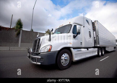 Bonnet blanc modern American popular big rig semi truck de livraison avec unité de réfrigération sur remorque semi réfrigérateur fonctionnant sur l'autoroute Banque D'Images