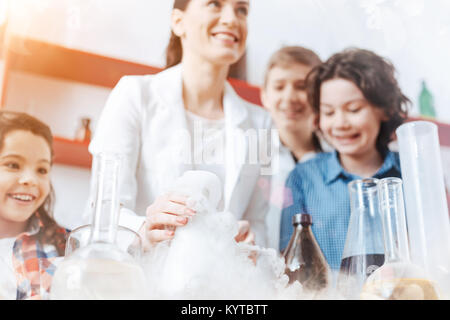 La science est amusant. Heureux les garçons et filles d'un sourire tout en prenant part à une session pratique détenus par leur professeur de chimie dans le laboratoire de l'école. Banque D'Images