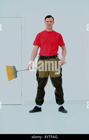 Portrait d'une ménagère dans un uniforme avec un balai isolé sur fond blanc. Banque D'Images