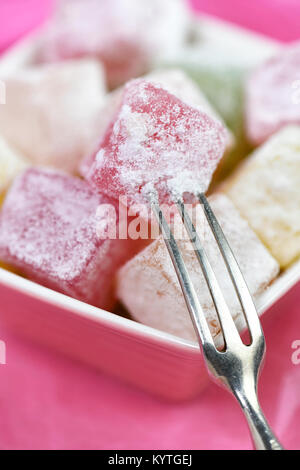 Plan macro sur de délicieux loukoums des dynamiques dans un petit plat avec un fond rose. prix pour le texte et l'espace de copie Banque D'Images