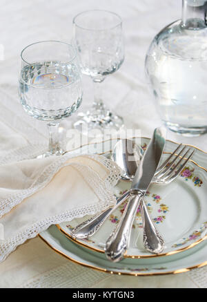 Dîner de luxe avec de l'argent ensemble couteau, fourchette et cuillère déposant au travers vaisselle en porcelaine, verres en cristal et sur nappe en dentelle vintage crème Banque D'Images