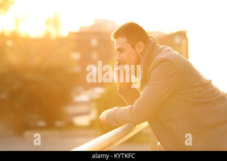 Vue latérale d'un portrait de l'homme graves dans une chambre balcon en hiver au coucher du soleil Banque D'Images