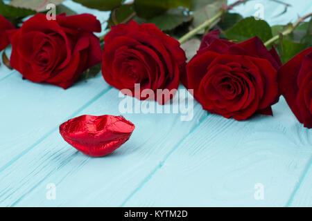 Roses rouges et rouge lèvres bonbons. Close up belle rose rouge pour la Saint-Valentin avec des bonbons en forme de lèvres, fond de bois. L'amour et de baisers. Banque D'Images