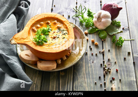 Soupe au potiron servi dans une citrouille évidée Hokkaido avec croûtons, persil, crème fraîche et herbes sèches. Arrière-plan de l'alimentation de l'automne. Banque D'Images